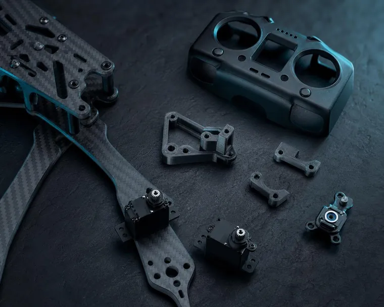 Drone arm, servos and printed brackets laid out on slate